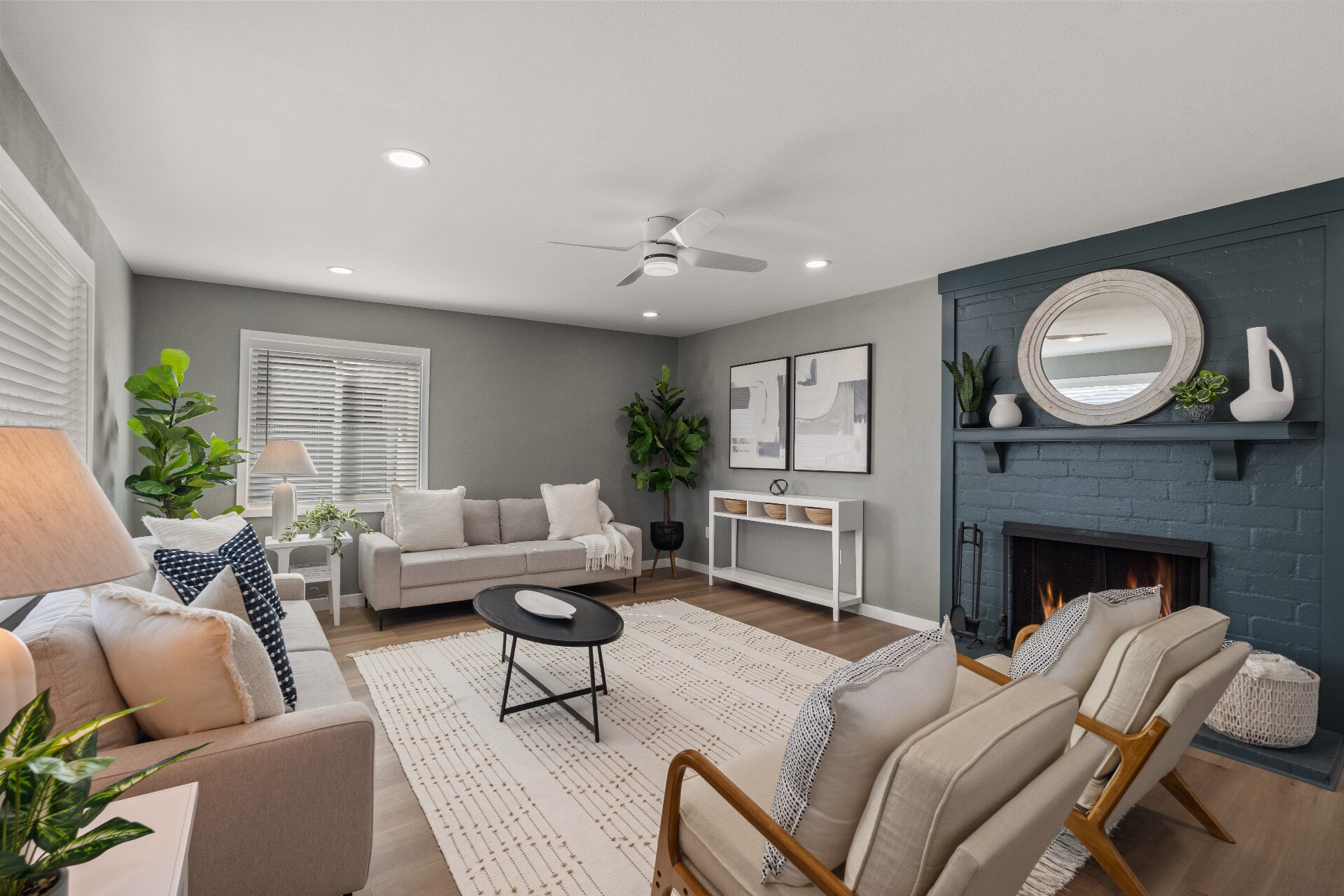 Warm staged living room with painted brick fireplace, layered seating, and natural light